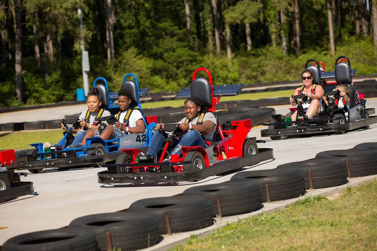 A lively go-kart racetrack bustling with participants zipping around tight curves. The scene radiates fun and excitement, perfect for thrill-seekers and groups looking to create lasting memories.
